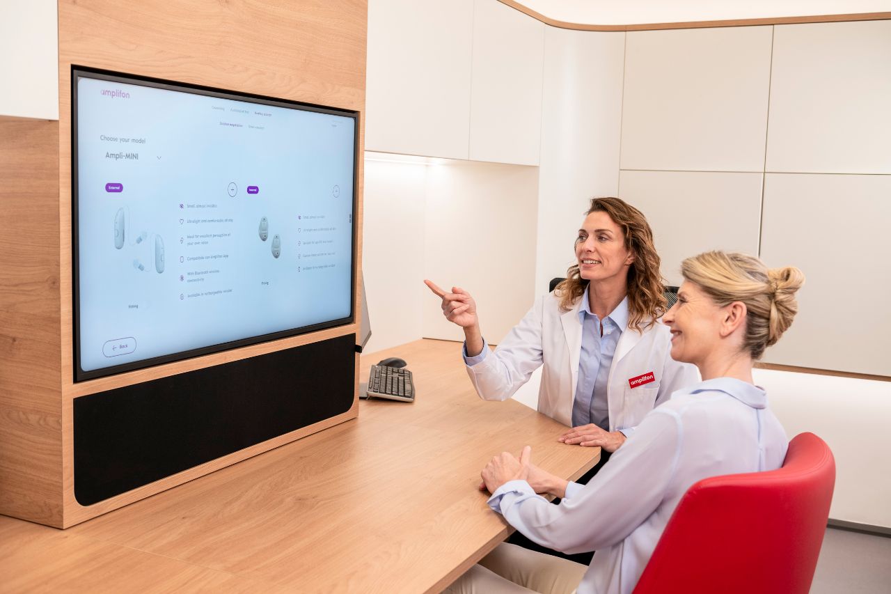 People sitting around a desk while one shows graphs on a computer