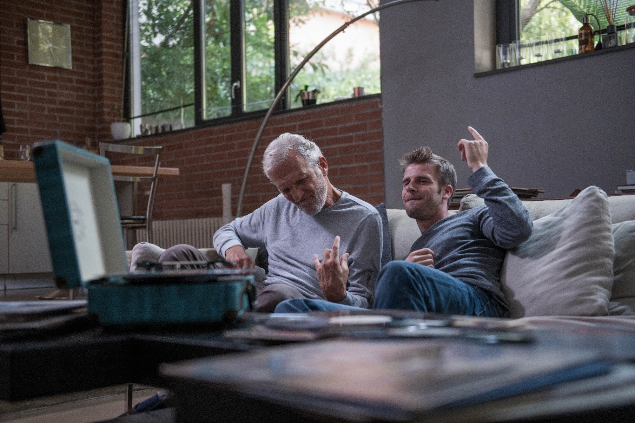 A father and son listening to music on the sofa