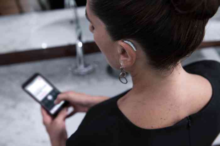 A woman is checking her hearing aid's app from her smartphone