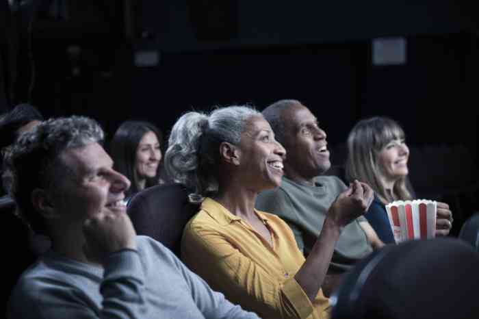 A woman laughs watching a movie at the cinema wearing her hearing aid