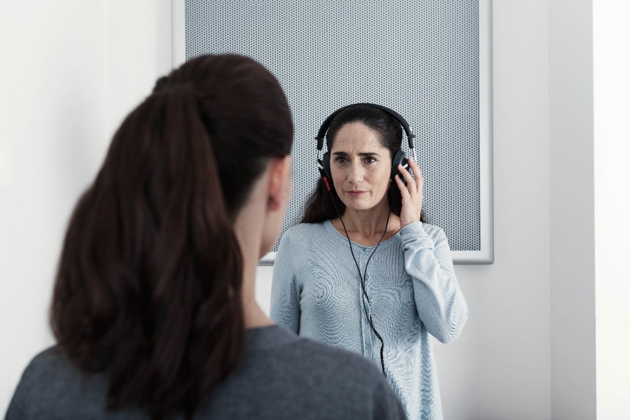 An audiologist by the Amplifon center doing a hearing test and a patient with headphones