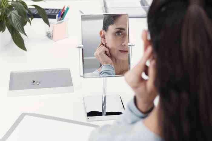 A woman wearing her earrings next to her hearing aid