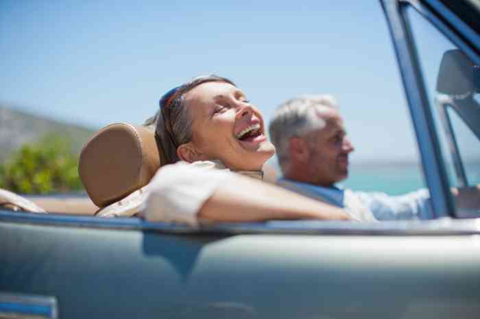 a woman smiling in a car with a man with sea in the background