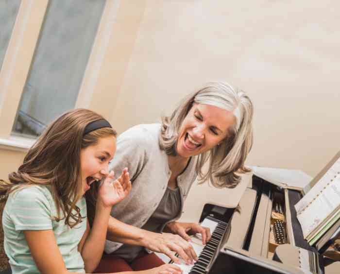 grandmother and granddaughter having fun playing the piano