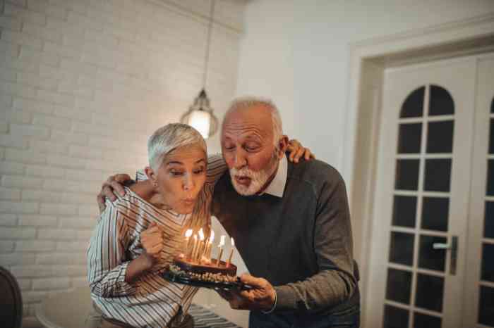 a couple of elderly people blowing out candles on a birthday cake
