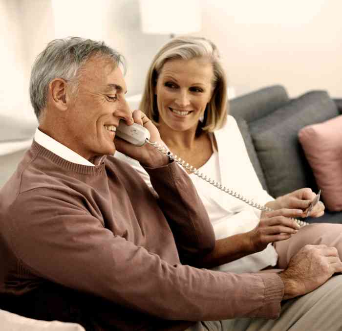 elderly woman and elderly man on a sofa talking on the phone