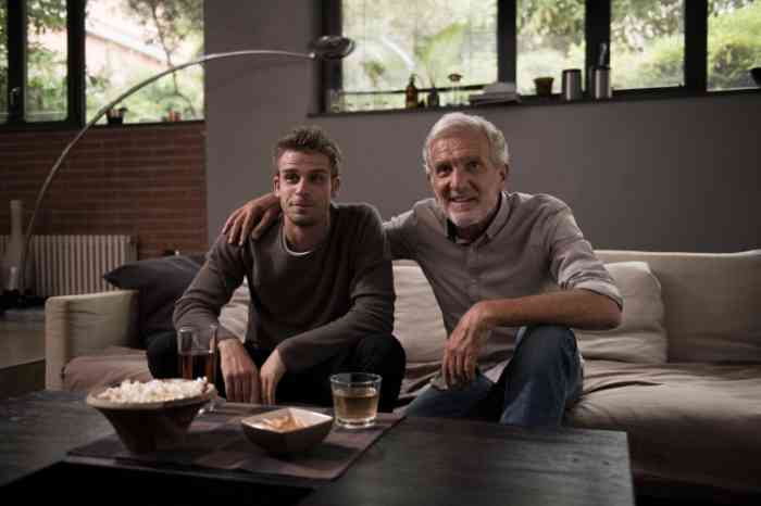 grandfather and grandson watching tv on the sofa with snacks and pop corn