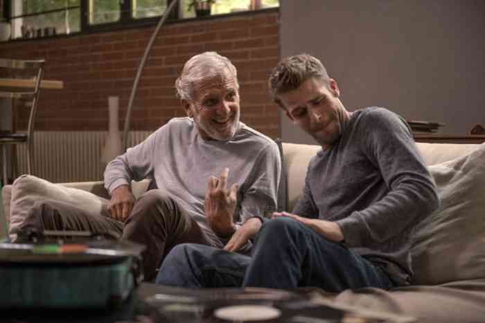a grandfather and his grandson listening to music on the sofa