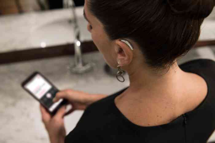 a girl looking at her smartphone connected with her hearing aids