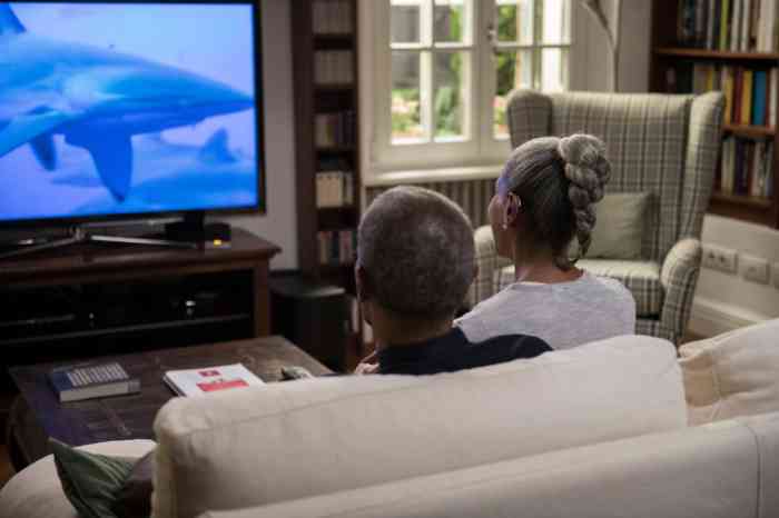 a woman wearing hearing aids and watching a movie with her husband at home