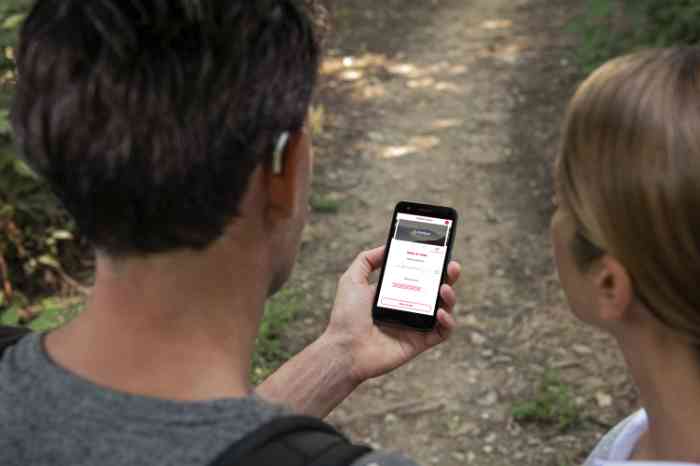 a girl and a man with hearing aids looking at Amplifon app on a smartphone