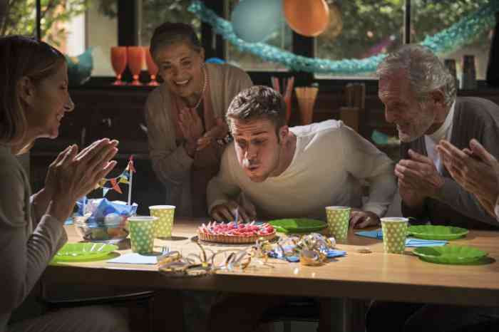 a boy celebrating his birthday with family and a cake