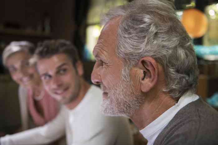 Older man sitting next to two younger relatives