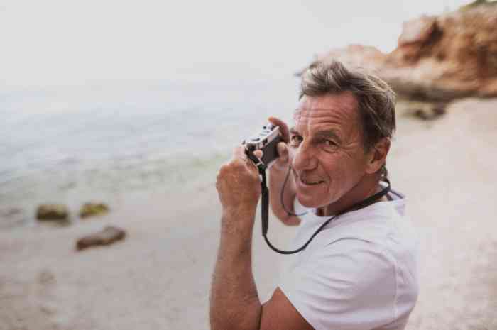 an elderly man taking photo on the beach