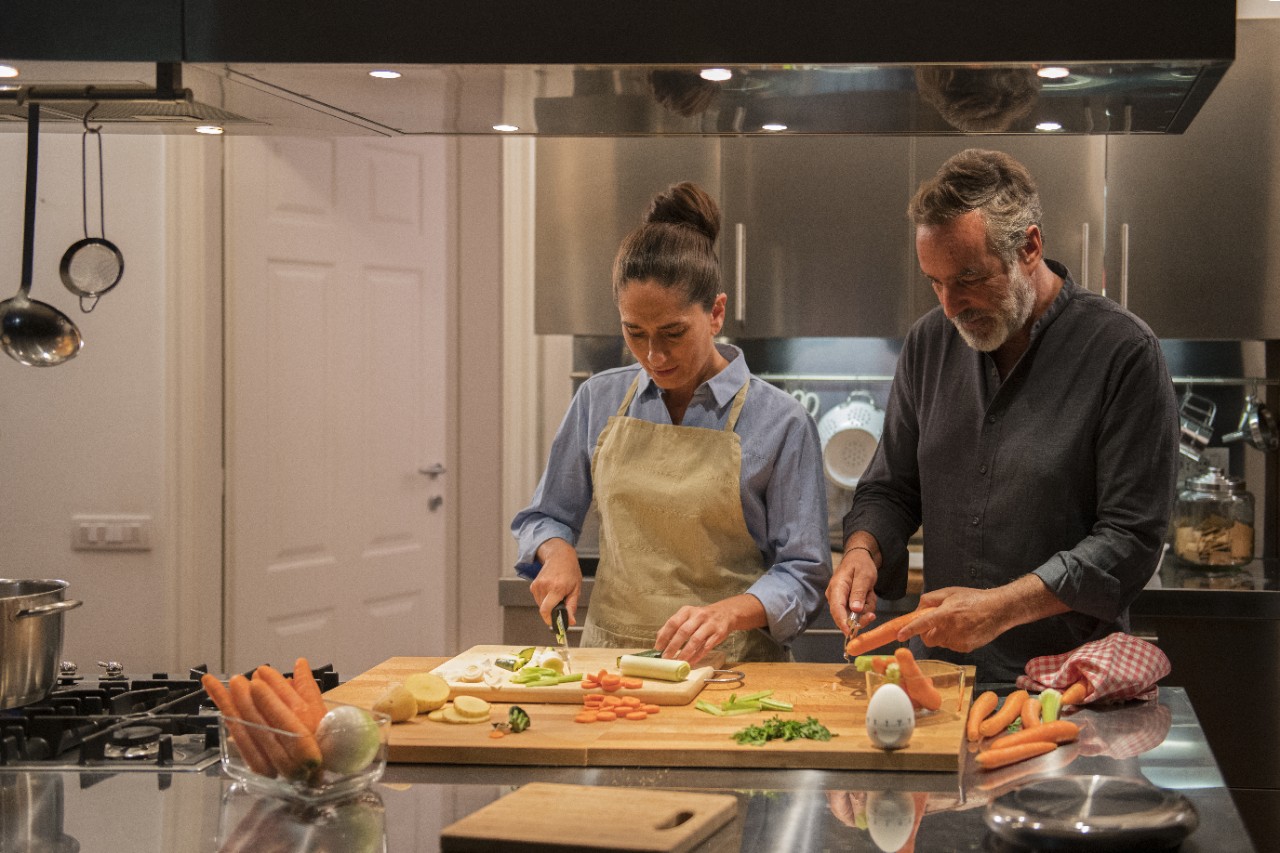 a couple making dinner together in the kitchen cutting vegetables