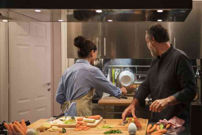 a woman and a man cooking dinner in their kitchen