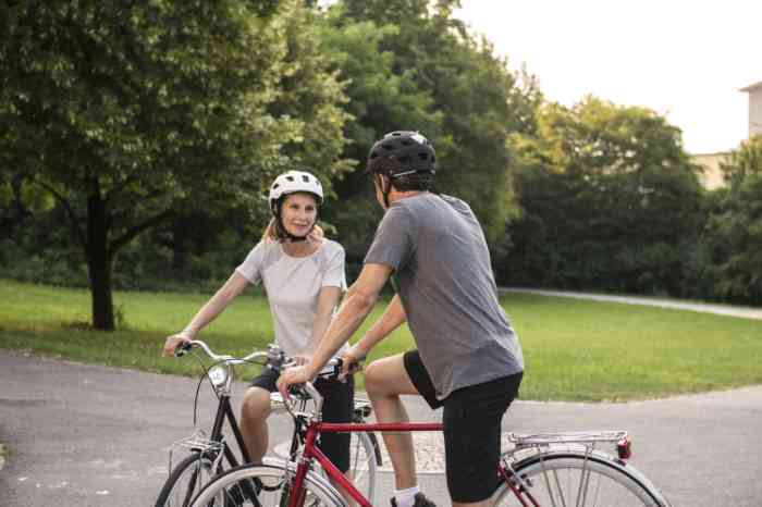 two people talking together on their bycicles wearing helmets