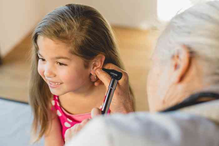 An audiologist checks a little girl's ear