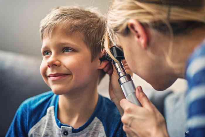 An audiologist checks a little boy's ear