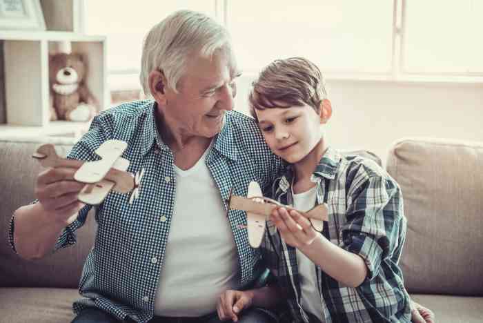 a grandfather and his grandson are playing together with wooden airplanes