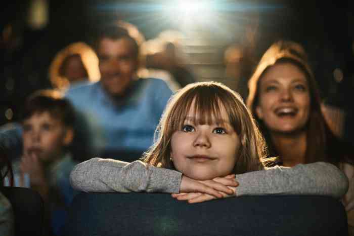 a little girl smiling watching a movie at the cinema
