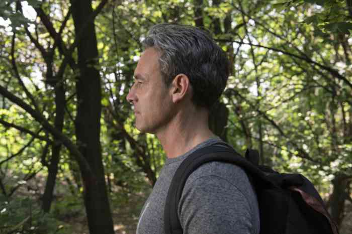 a man with a black backpack doing a walk in the forest