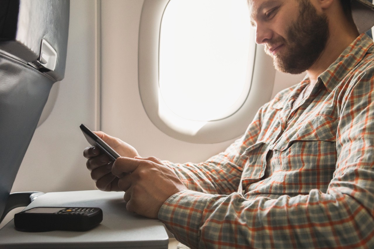 A man on a plane using his smartphone