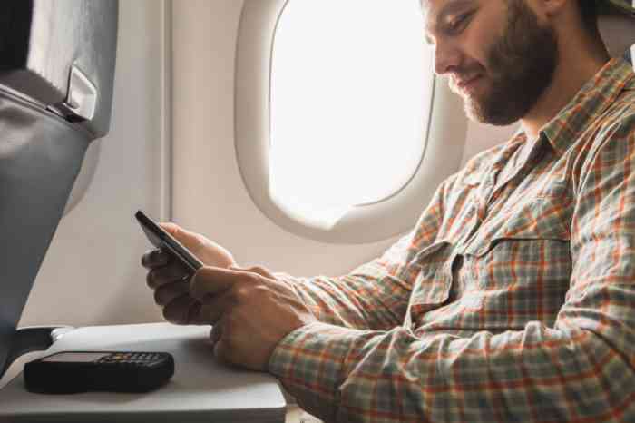 A man on a plane using his smartphone