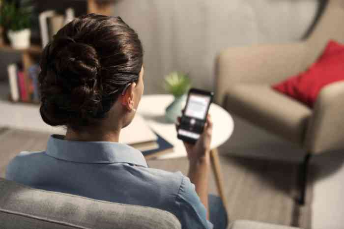 a woman wearing a hearing aid and using a smartphone in her living room