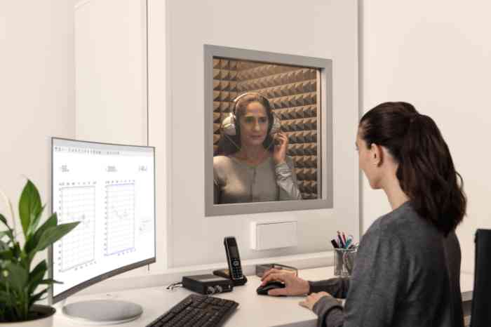Person undergoing a hearing check in a room while the employee checks the results on the computer