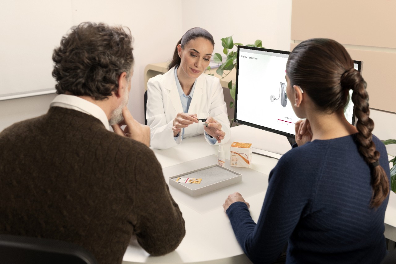 Employee explaining the hearing aids to two clients
