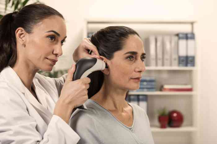 an audiologist doing an hearing test on a woman in a national hearing care center