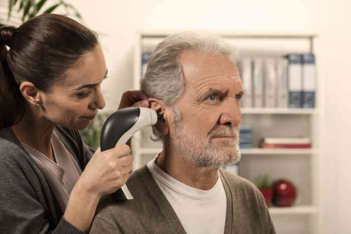 A woman checking at an elderly man's ear