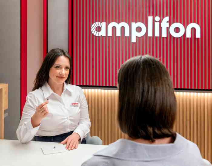 Amplifon audiologist showing a hearing aid to a customer