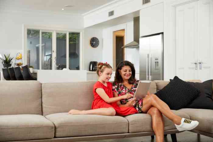 A child and a woman reading an iPad on the couch