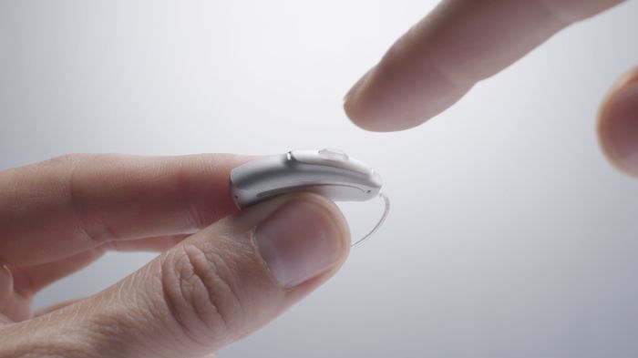 someone testing the control button of one hearing aid