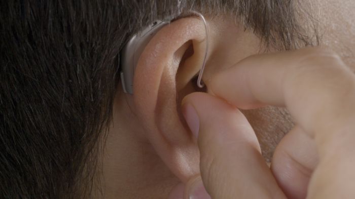 a man placing his ric hearing aid in the ear