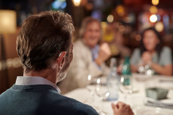 Man from behind sitting at the table with other people during dinner