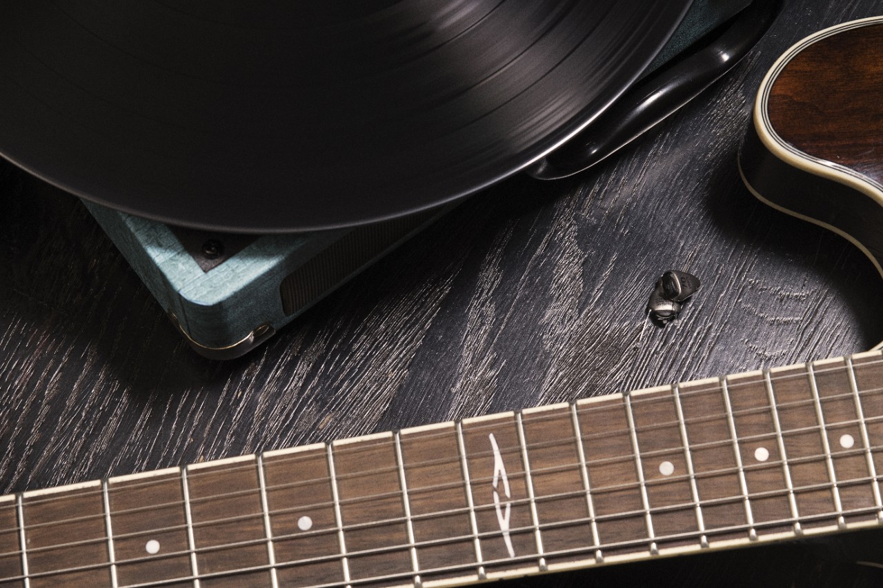 in the ear hearing aid: an invisible hearing aid laid on the floor near a guitar and a vinyl