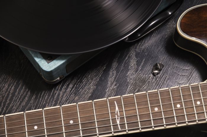 in the ear hearing aid: an invisible hearing aid laid on the floor near a guitar and a vinyl
